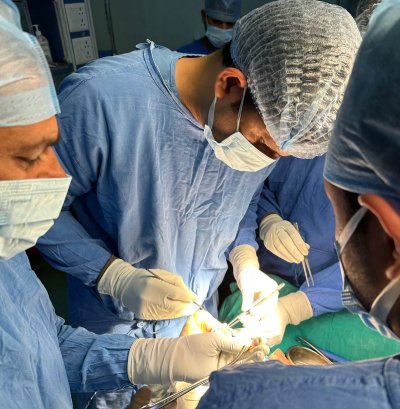 Dr. Ishwar Meena, a foot and ankle surgeon, performing surgery on a patient's foot in a brightly lit operating room.